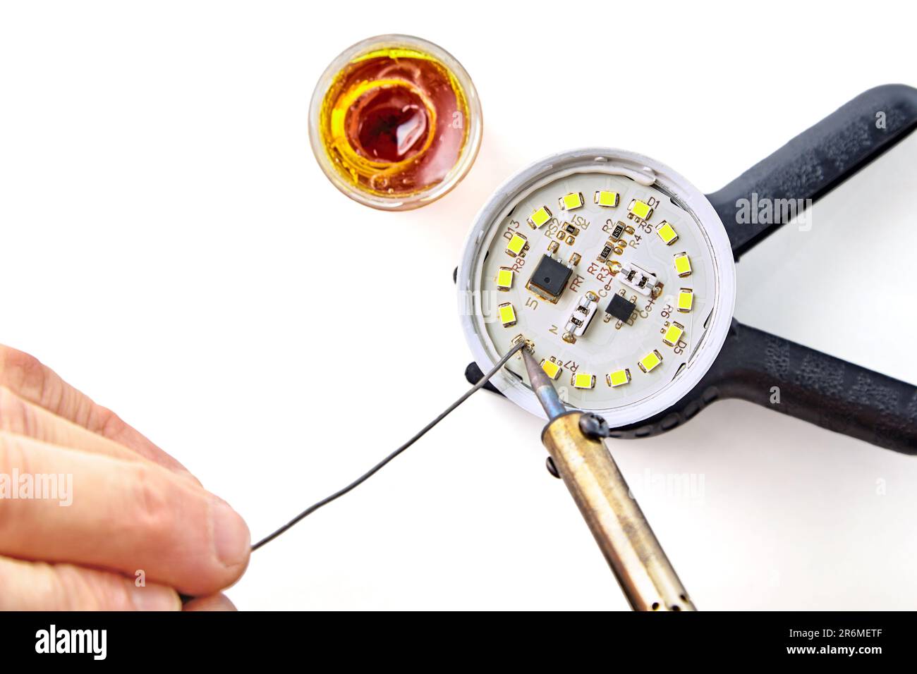 Soldering a burned-out LED into an LED light bulb. Hand with a soldering  iron and rosin with solder on a white background. Light bulb repair, family  b Stock Photo - Alamy