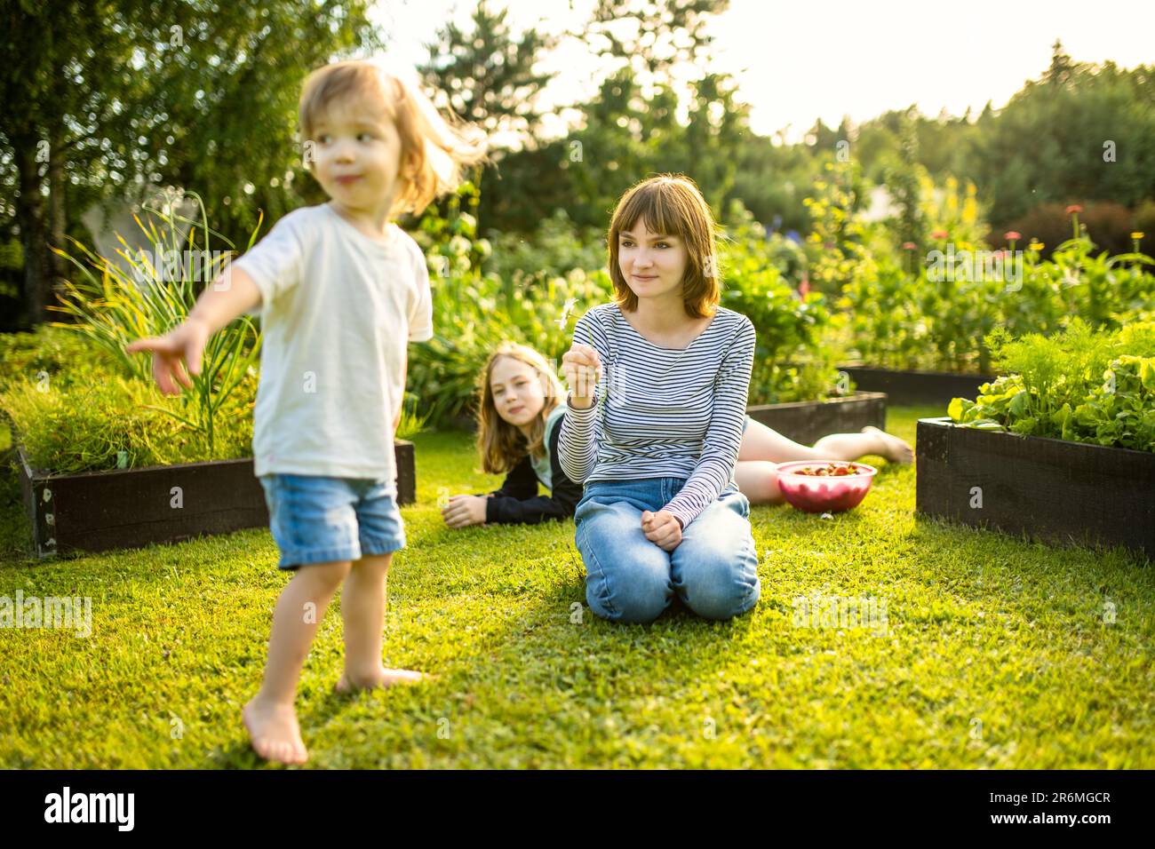 Two big sisters and their toddler brother having fun outdoors. Two