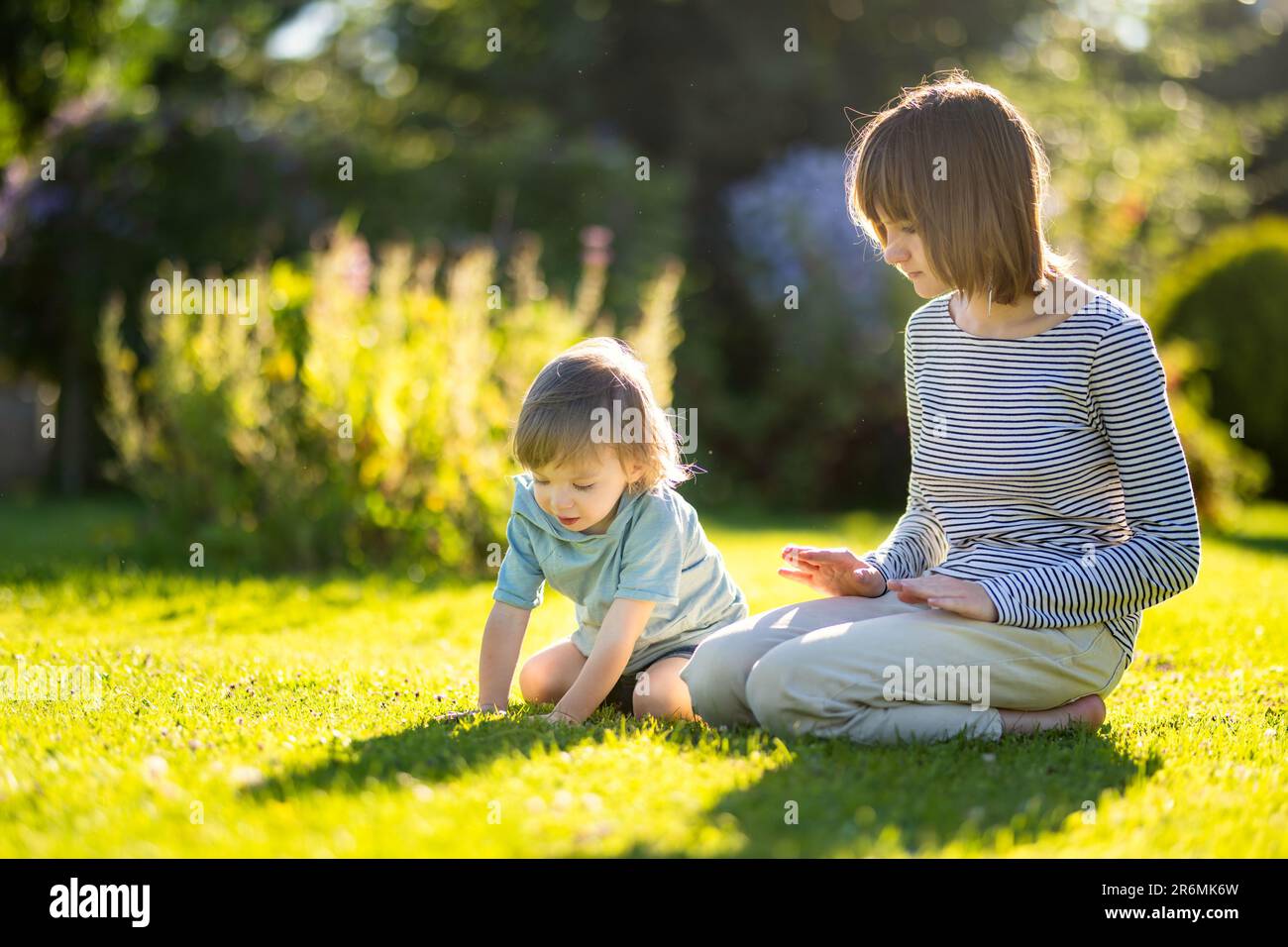 Cute big sister with her toddler brother. Adorable teenage girl holding