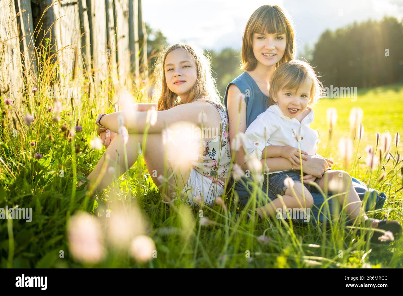 Two big sisters and their toddler brother having fun outdoors. Two