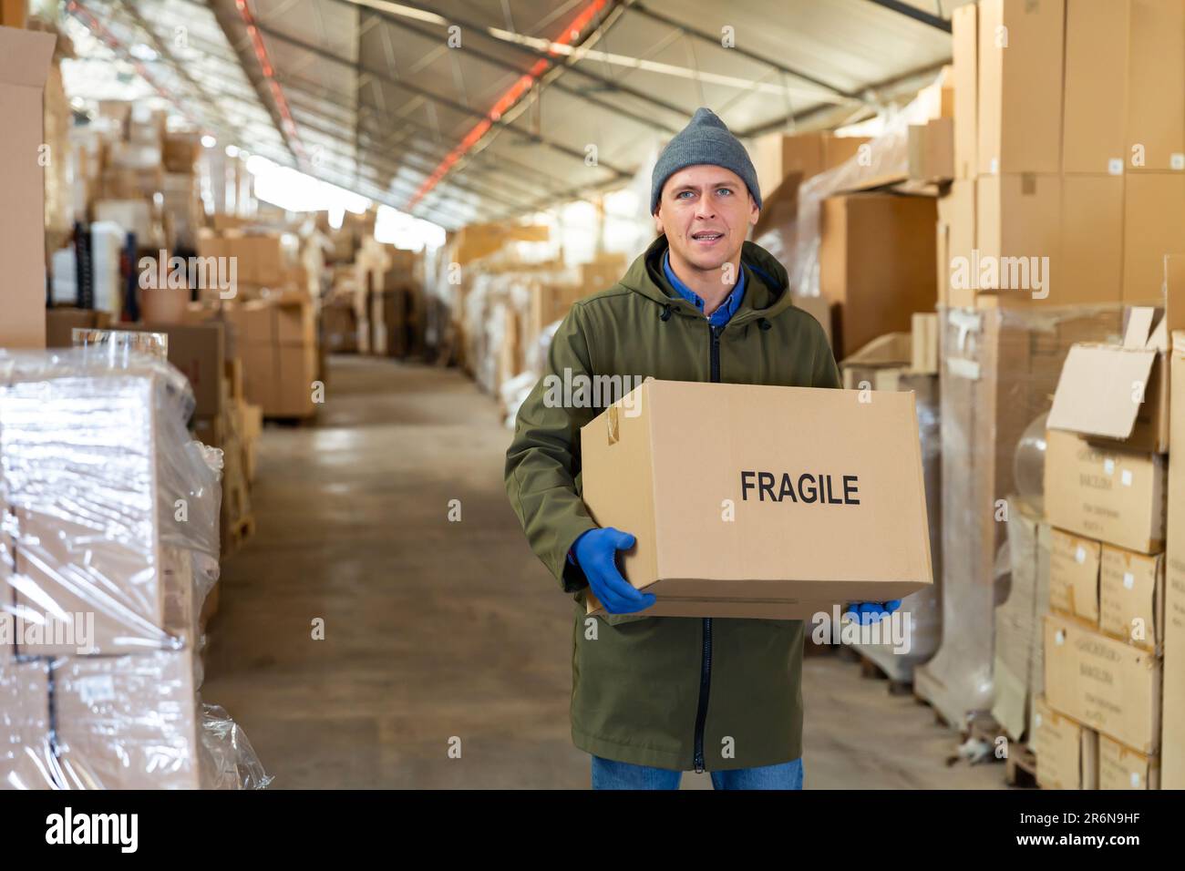Man worker carrying cardboard box with fragile content Stock Photo - Alamy
