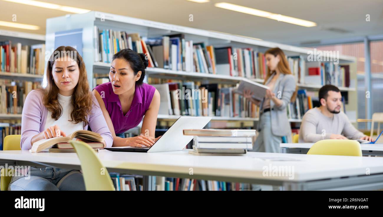 Two female colleagues working on joint project in library Stock Photo