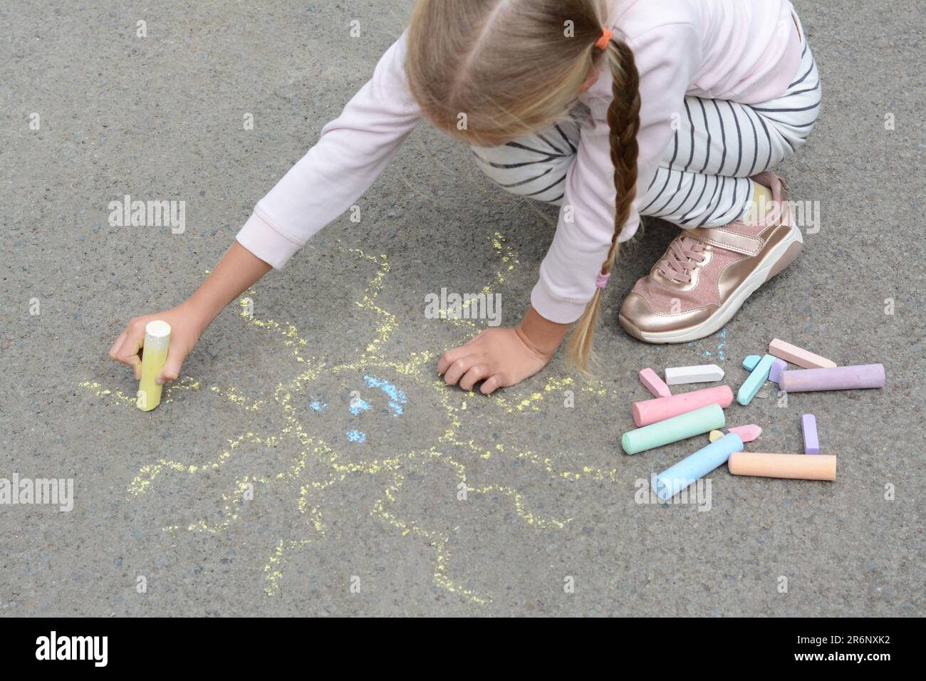 Little child drawing sun with chalk on asphalt Stock Photo - Alamy