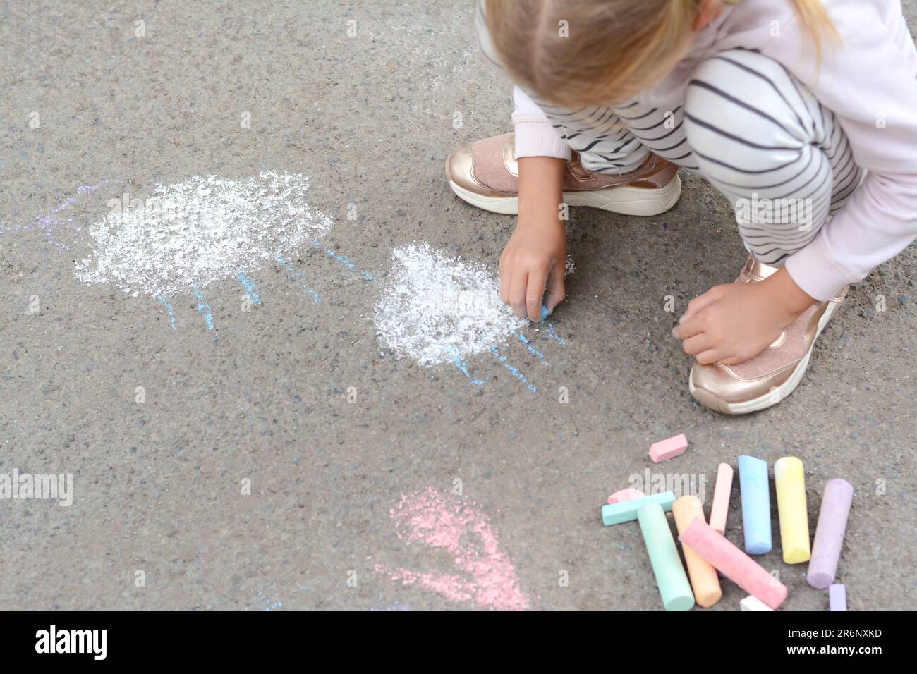 Little child drawing white clouds with chalk on asphalt, closeup Stock ...