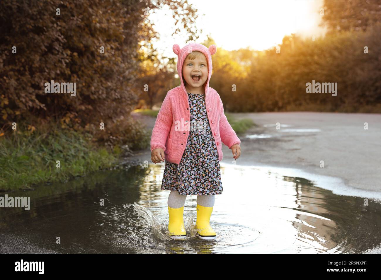 Little girl wearing rubber boots walking in puddle outdoors Stock Photo ...
