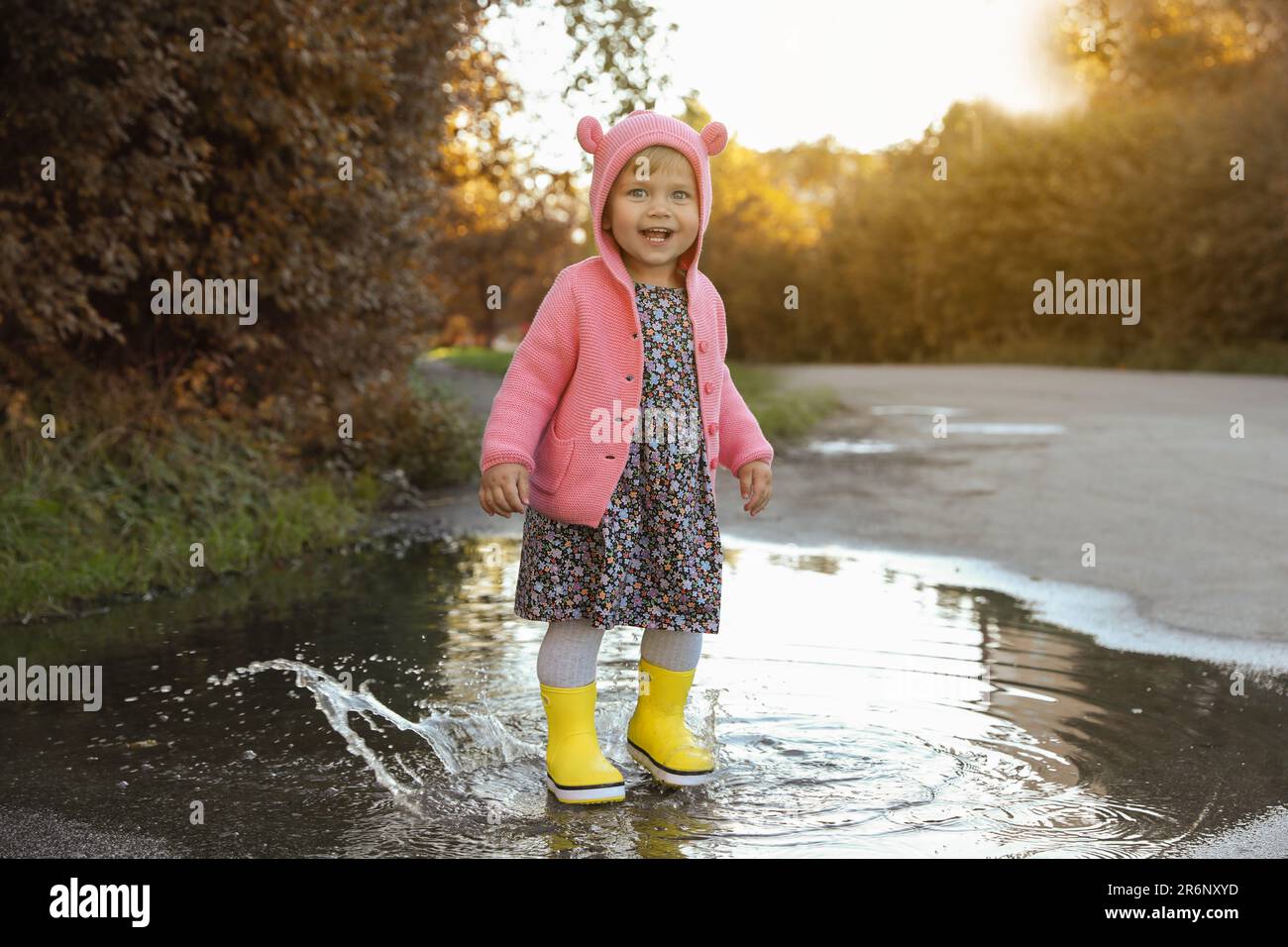 Little girl wearing rubber boots walking in puddle outdoors Stock Photo ...