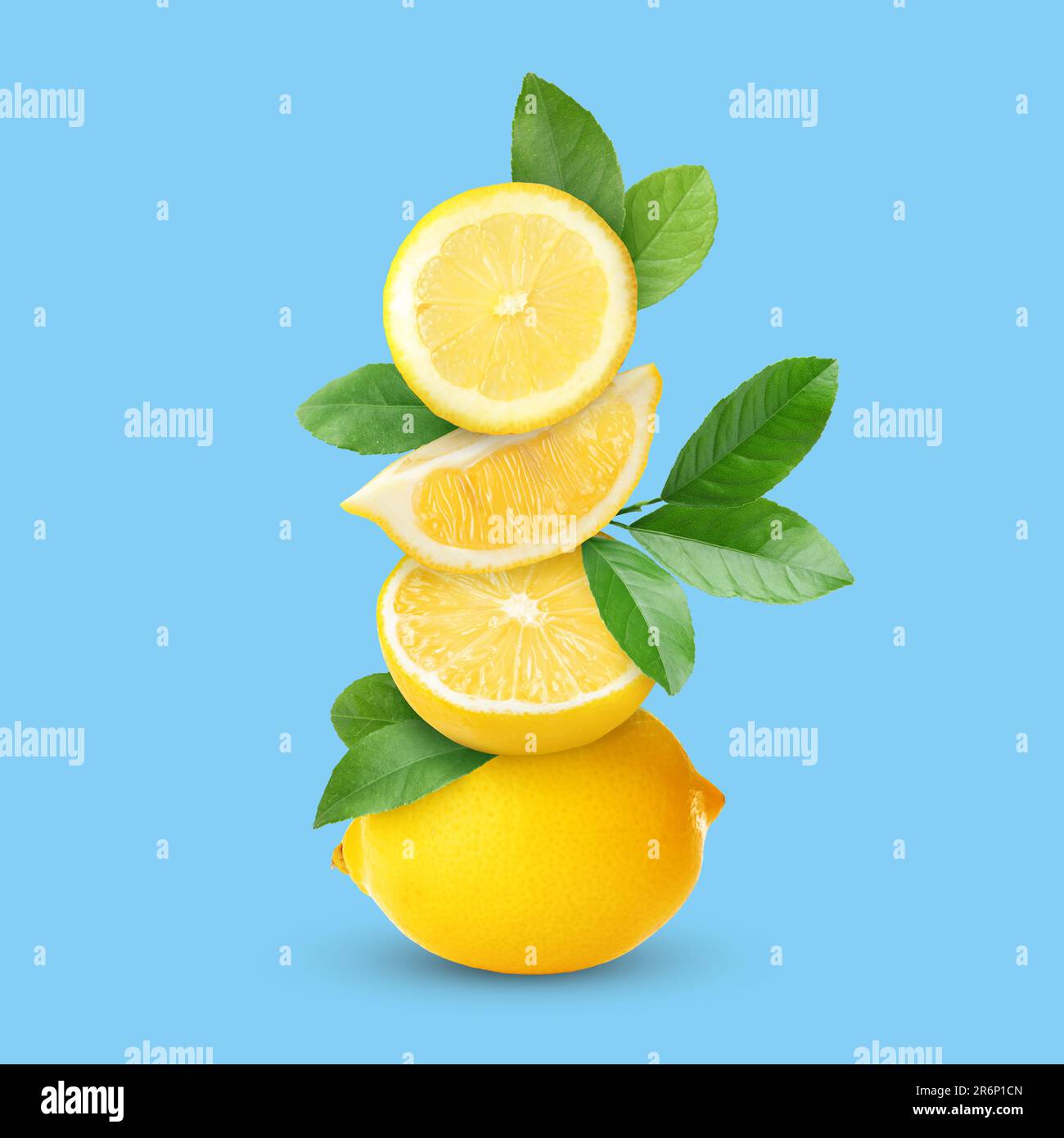 Stacked cut and whole lemons with green leaves on light blue background ...