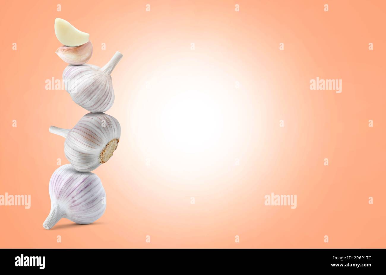 Stack of garlic bulbs and cloves on coral background, space for text ...