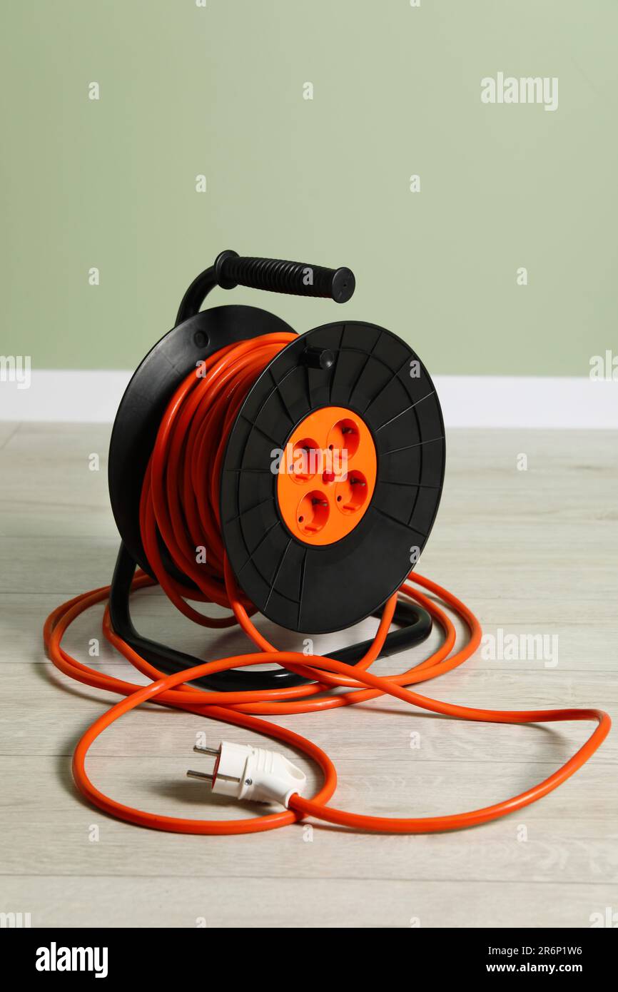Extension cord reel on floor near light green wall. Electrician's