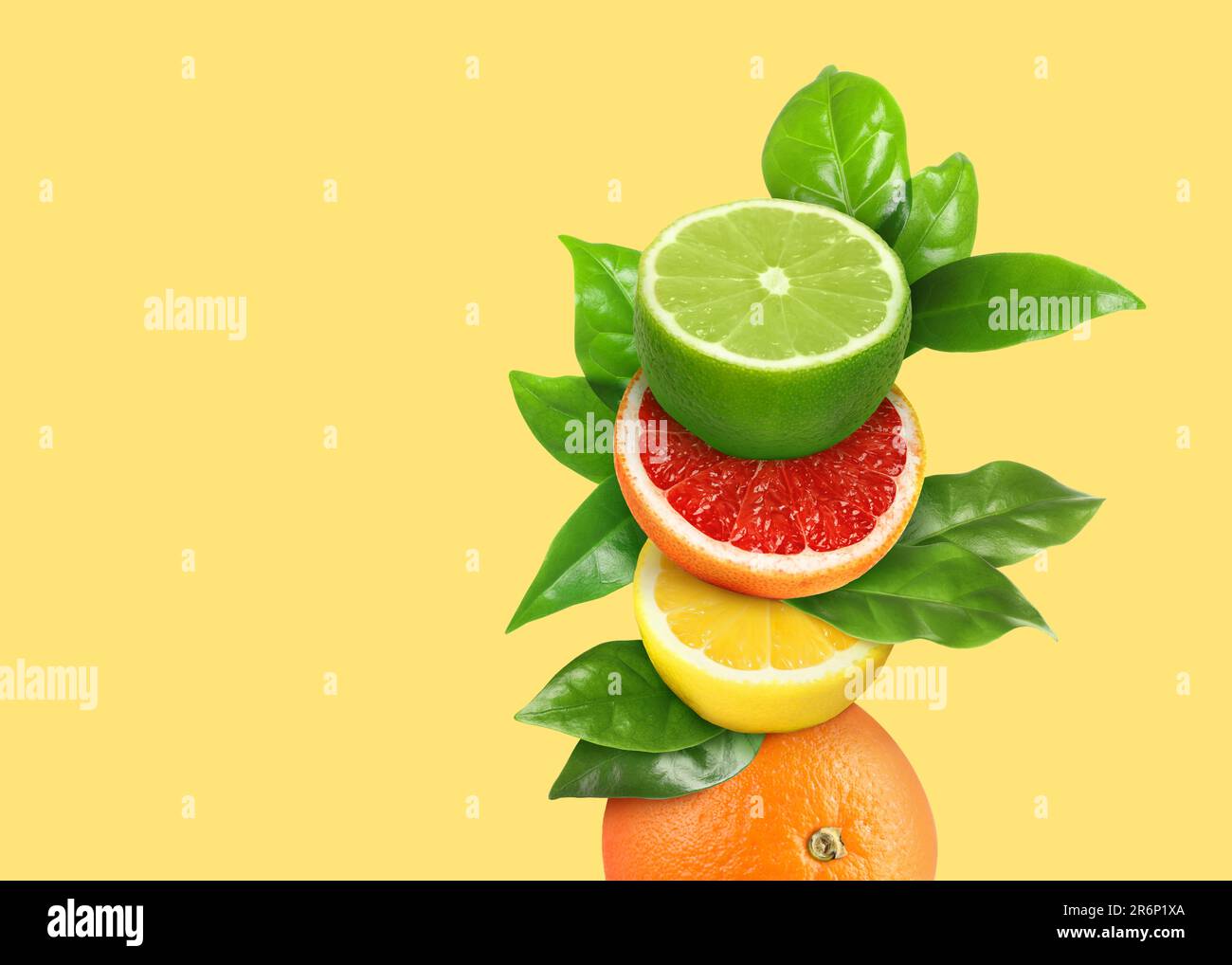 Stack of different fresh citrus fruits with green leaves on light