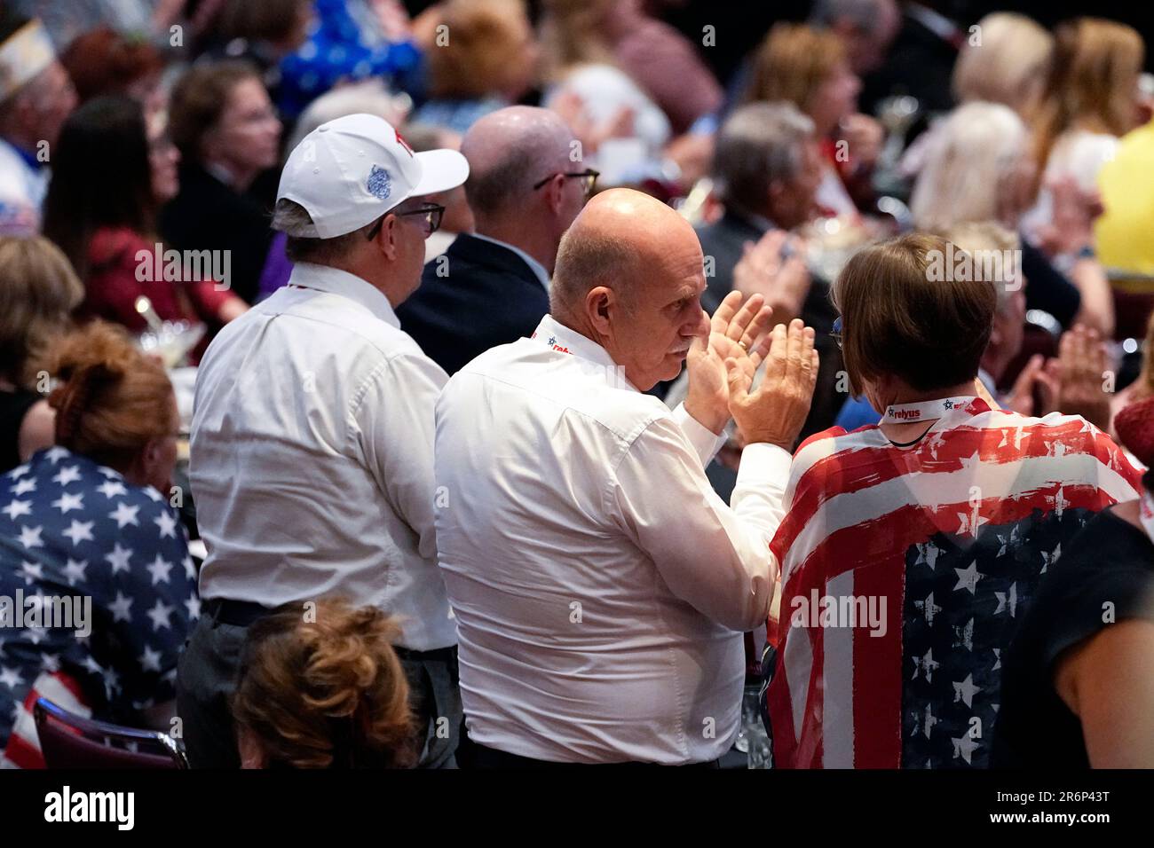 People in the crowd applaud as former President Donald Trump speaks
