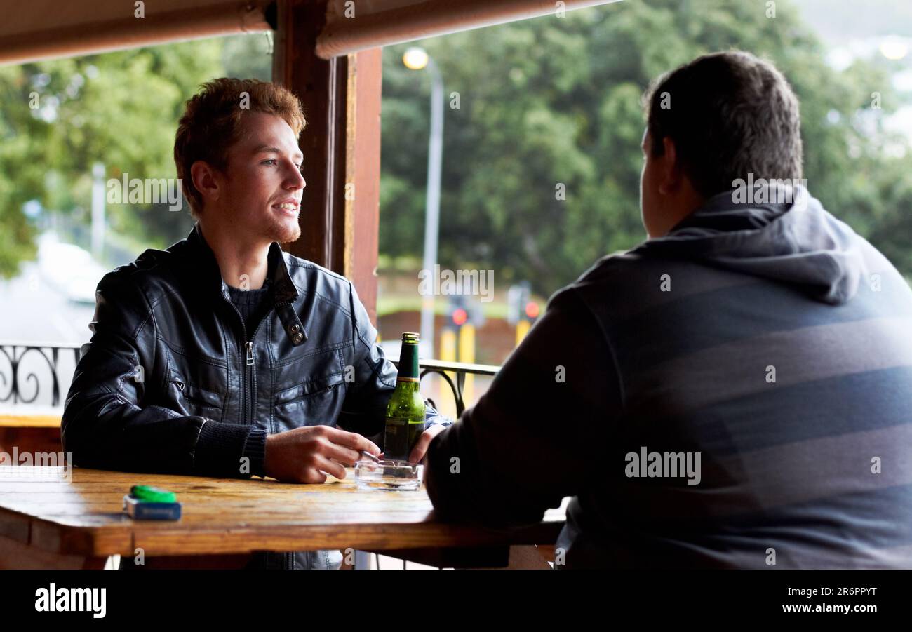 Men, friends and drinking beer at a pub and restaurant with conversation and discussion. Alcohol, guys and young people together at diner with alcohol Stock Photo