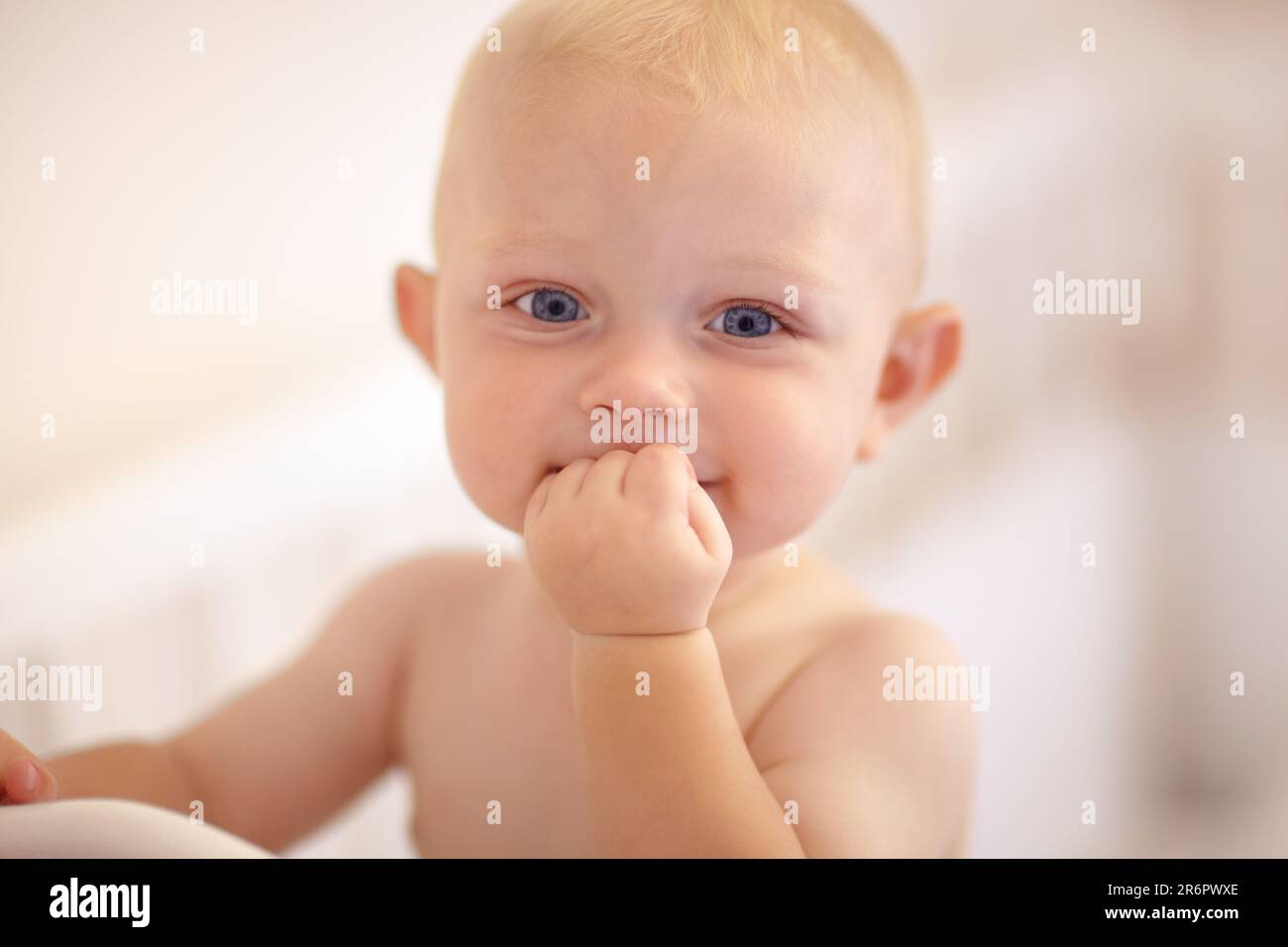 Happy, face and toddler standing in crib, bedroom or excited baby boy with hands on teething mouth in morning, nap or afternoon. Kid sitting in cot Stock Photo