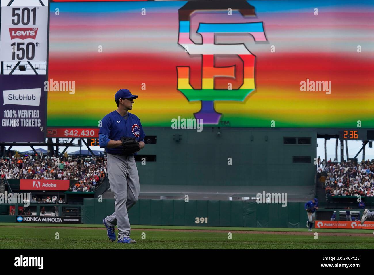 A sign for San Francisco Giants' Pride Day is shown on the video board as  Chicago Cubs pitcher Kyle Hendricks walks toward the dugout after retiring  the Giants in the fifth inning