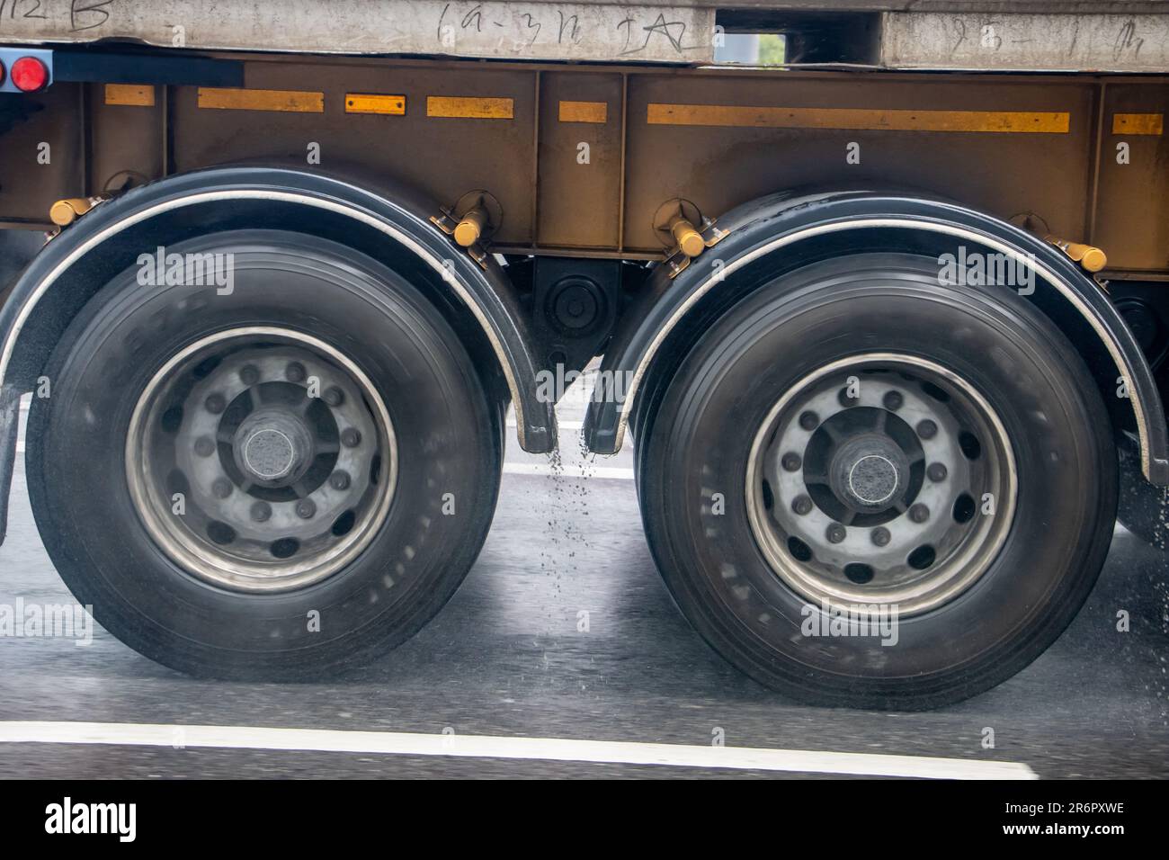 Detail of the wheels of a truck driving on the road in the rain. Stock Photo