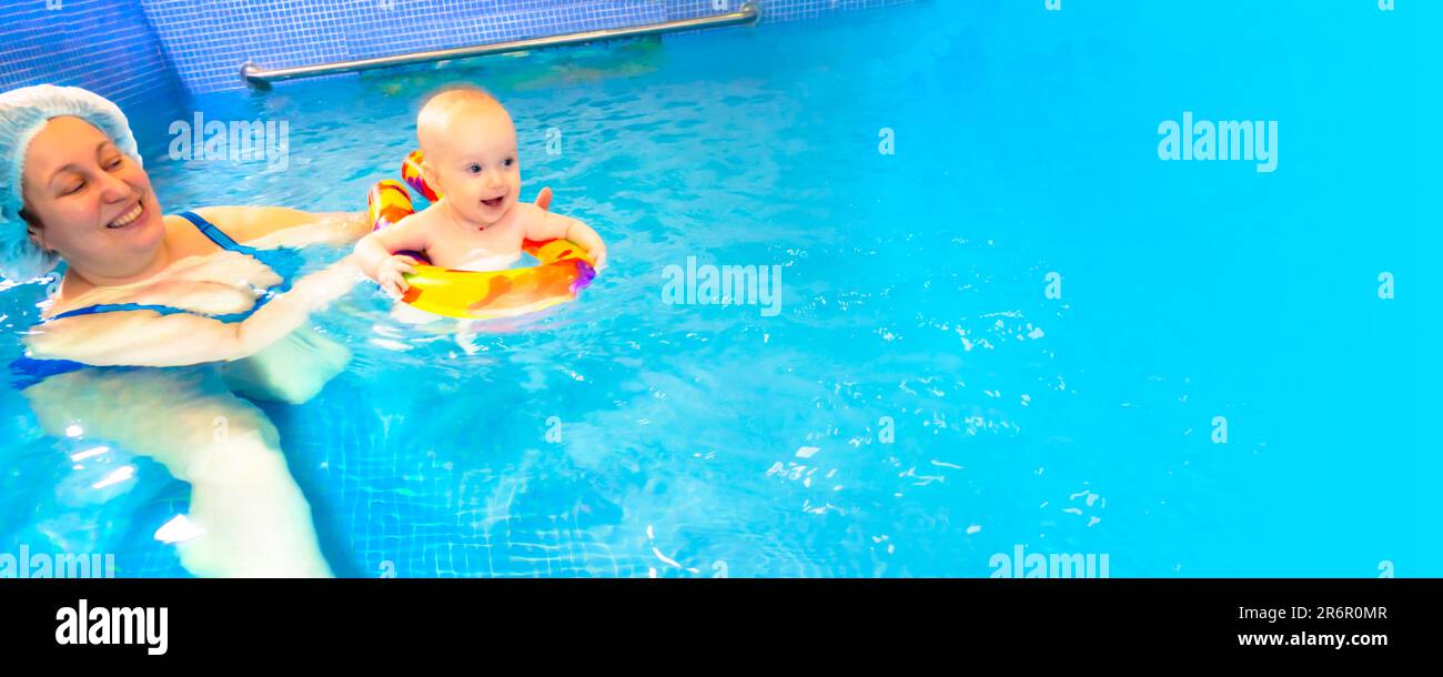 Adorable baby girl enjoying swimming in a pool with her mother early development class for