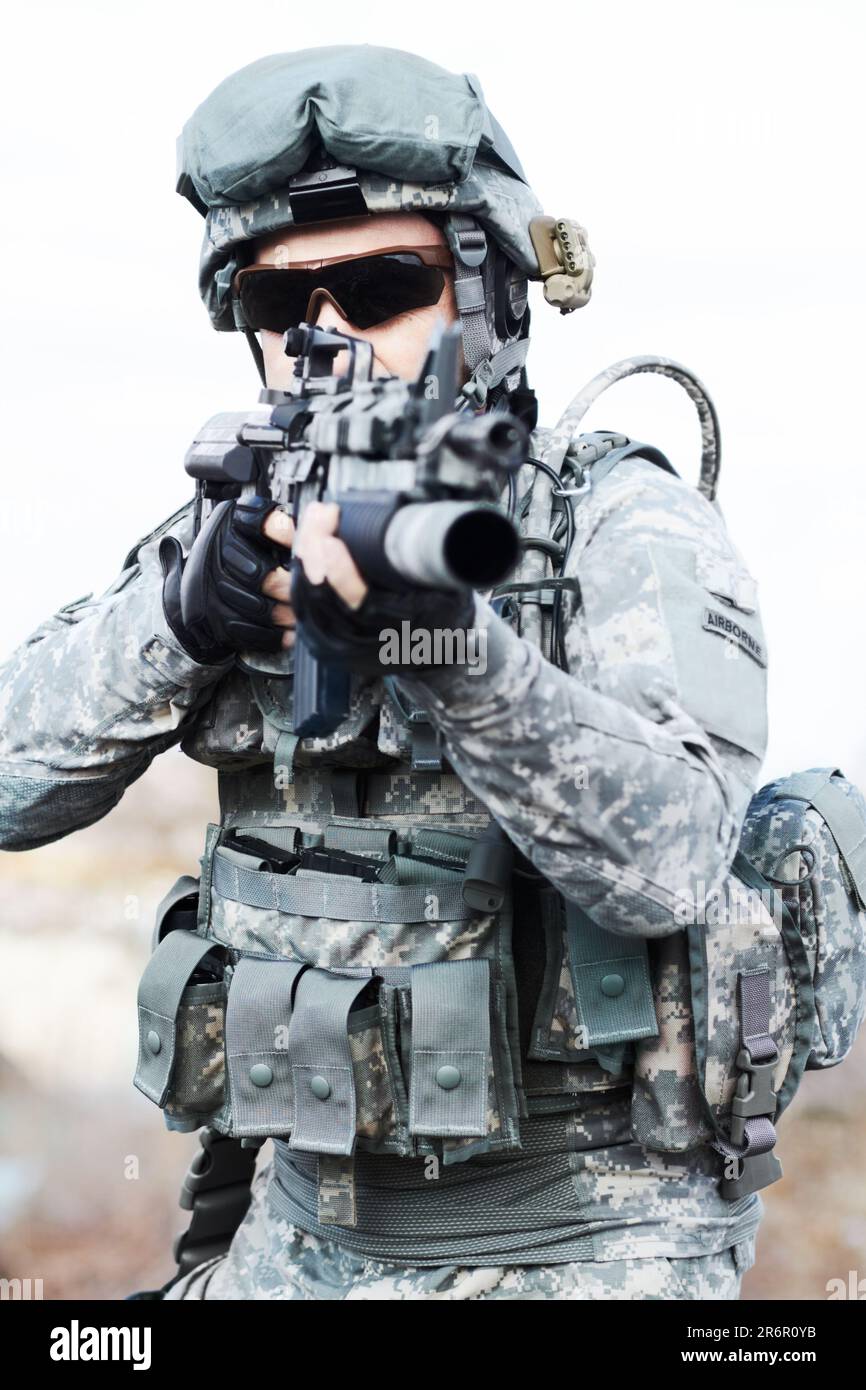 Soldier man, gun and outdoor with aim, field and nature for war, fight and army in countryside. Military service, battlefield and agent with machine Stock Photo