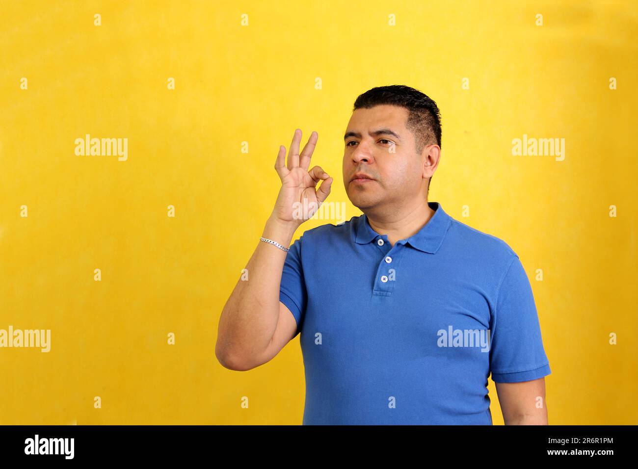 Dark-haired 40-year-old Latino man shows Mexican sign language used to communicate between the deaf and dumb Stock Photo