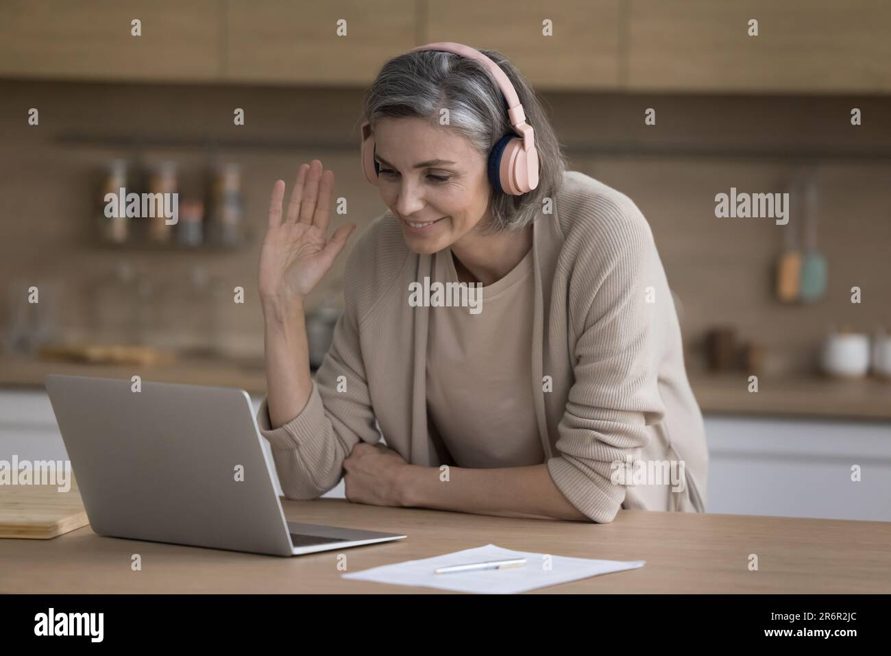 Happy mature woman in wireless headphones talking on video call Stock ...