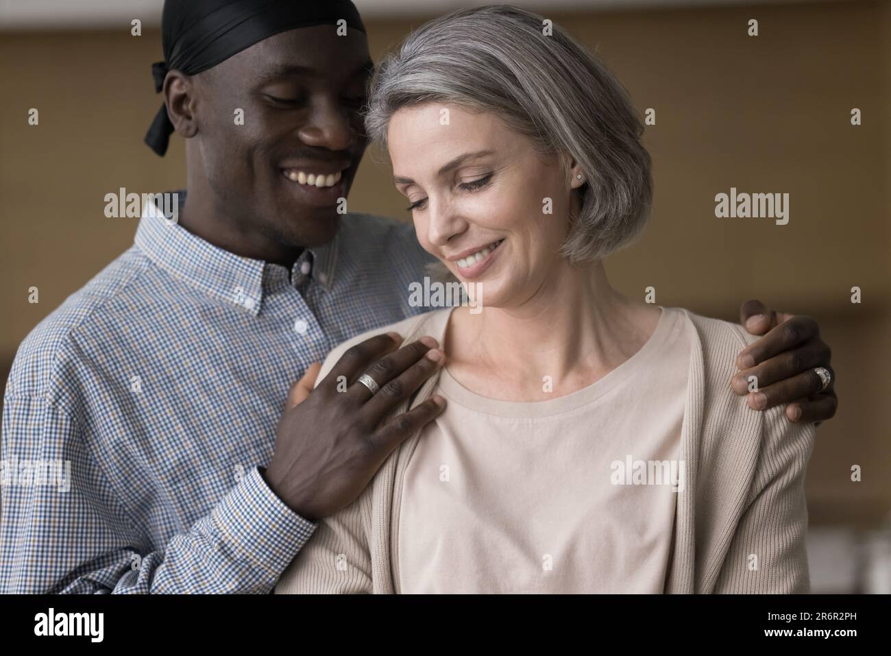 Happy handsome young African man hugging pretty grey haired girlfriend Stock Photo
