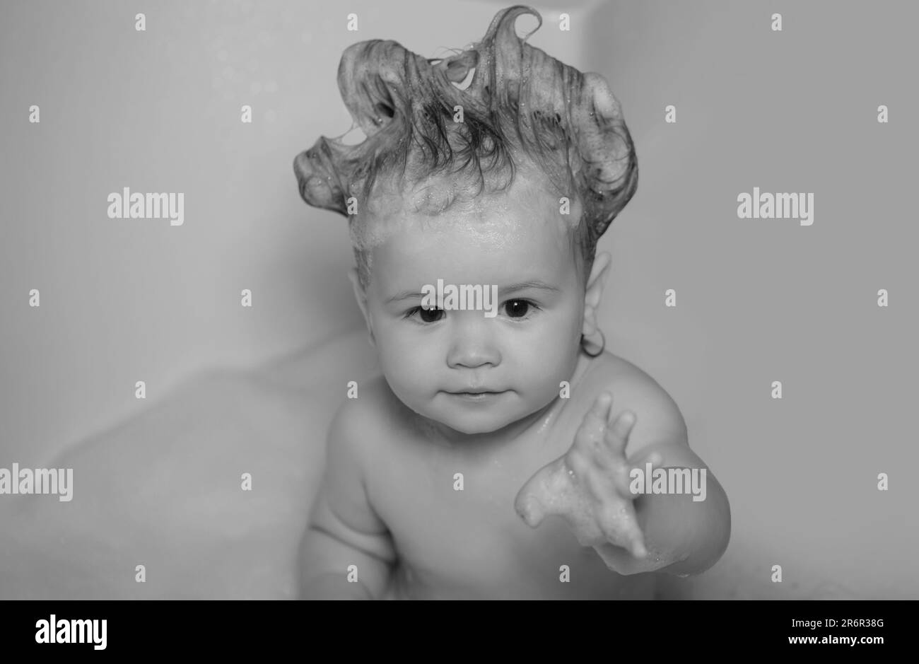 Todler in shower. Kid in bathtub with fluffy soap bubble. Baby