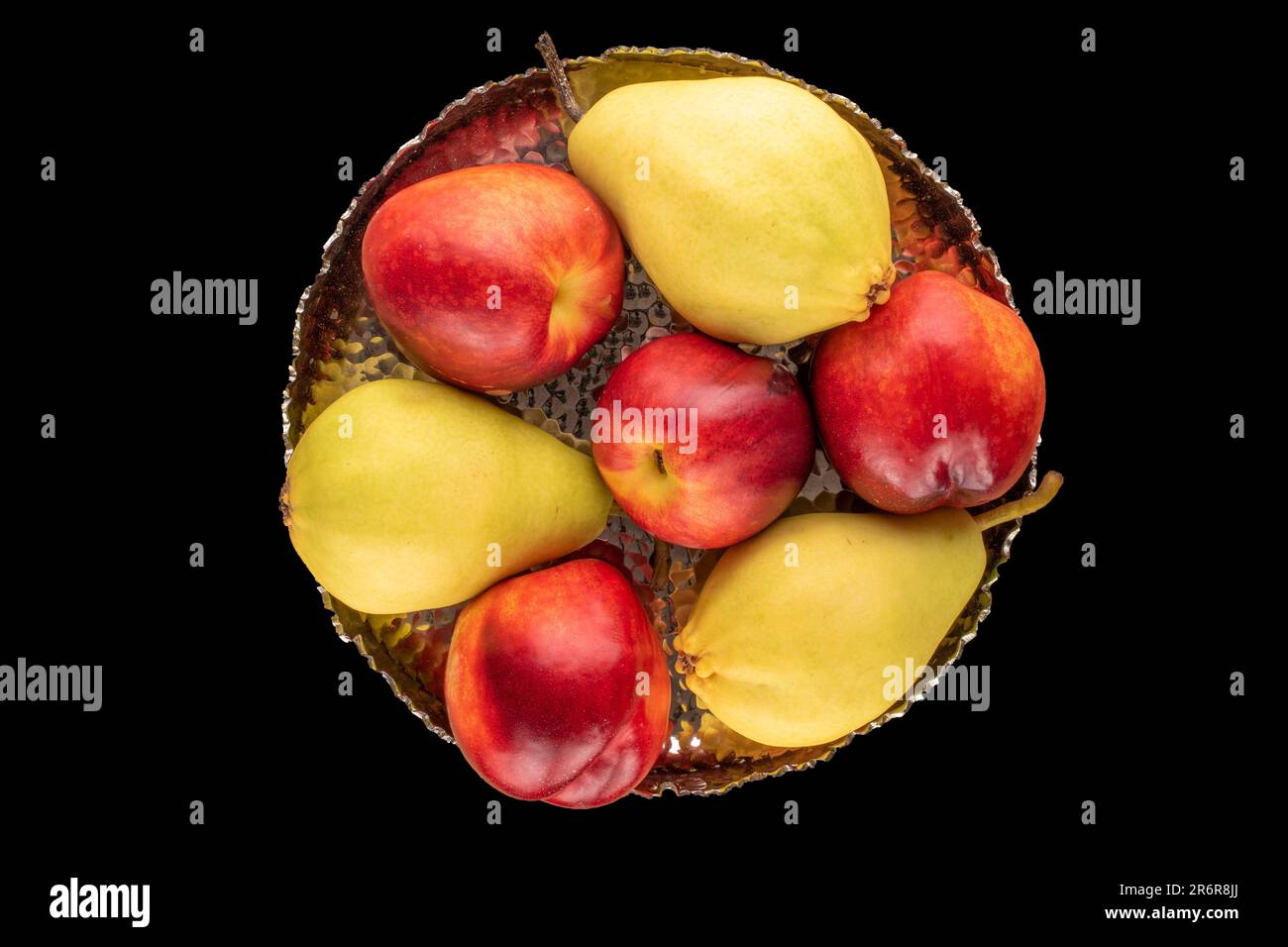 A few ripe nectarines and a pear with a metal vase on a black background, macro, top view. Stock Photo