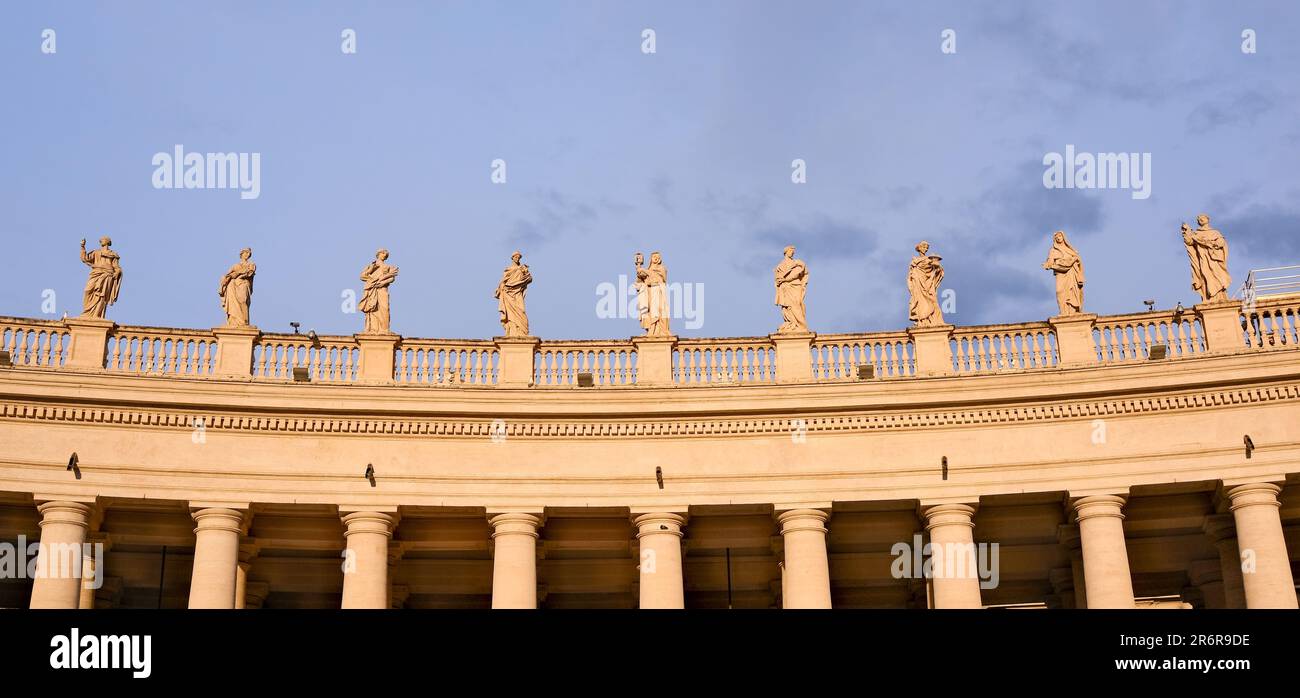 A group of statues stand atop the ornate roof of a grand architectural building in Vatican Stock Photo