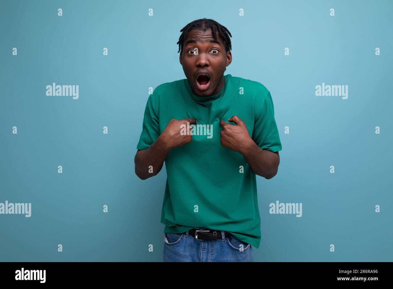surprised confused brunette model stylish dark-skinned man in a t-shirt on a blue background Stock Photo