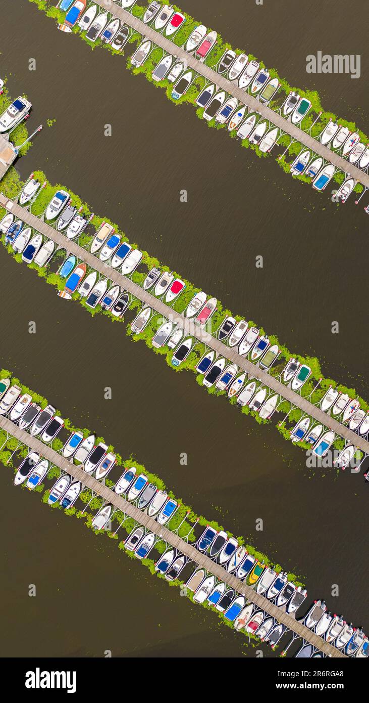 An aerial view of a marina with several boats and yachts docked in calm ...