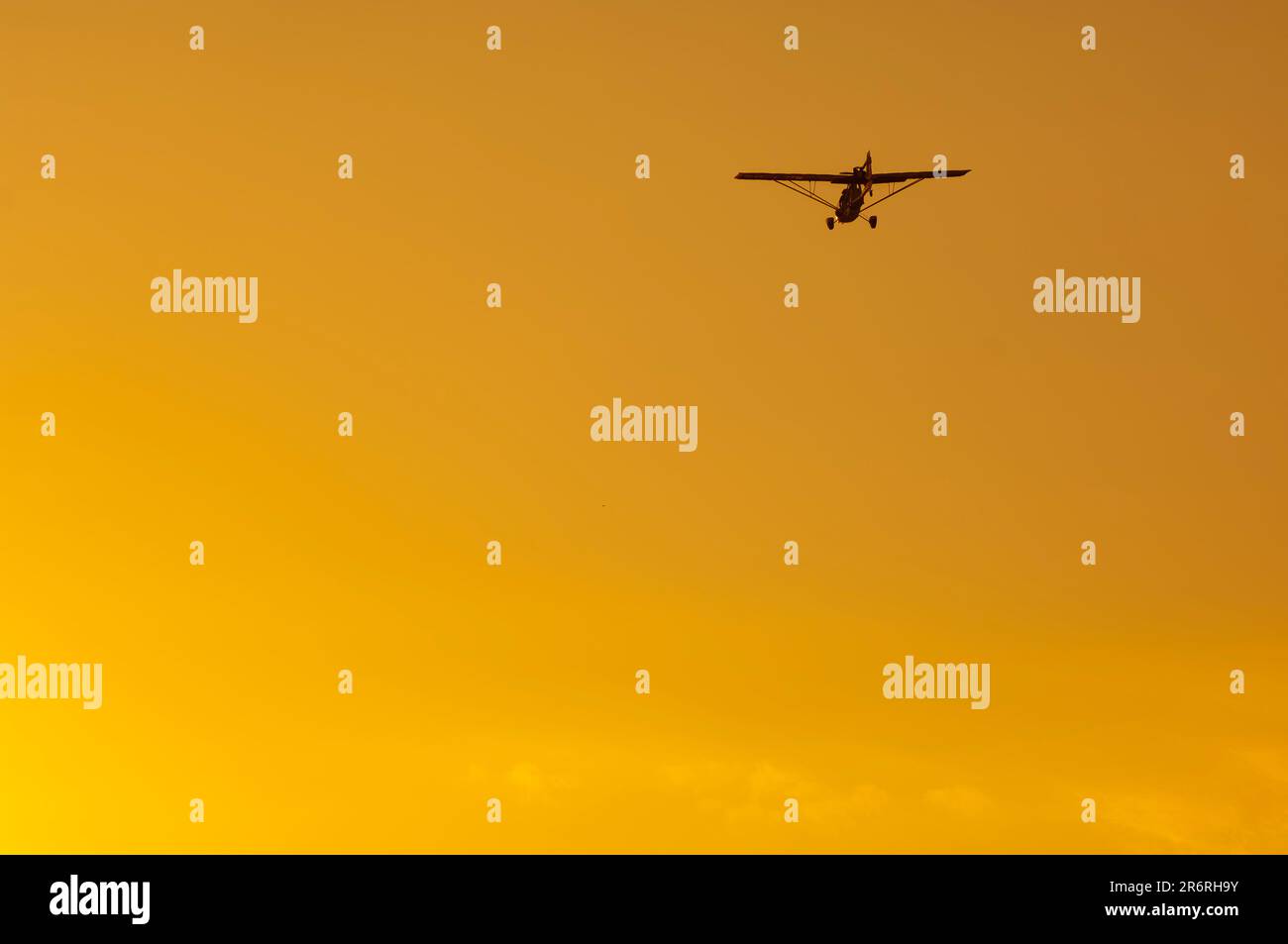 Ultralight plane silhouette in orange sky at sunset Stock Photo