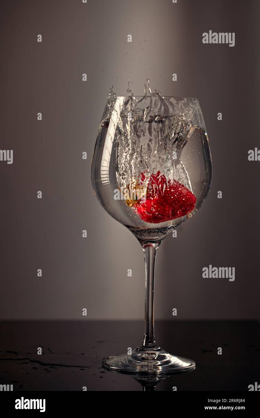 Strawberries dropped into a glass of water. Stock Photo