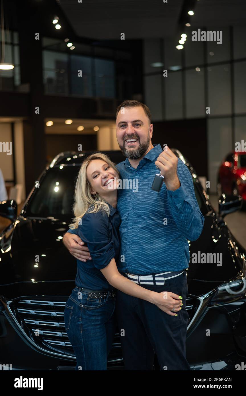 Happy caucasian couple hugging and man holding new car keys in car ...