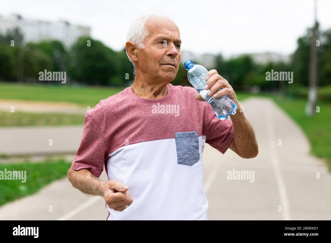 Old man with bottle of water standing outdoors Stock Photo - Alamy