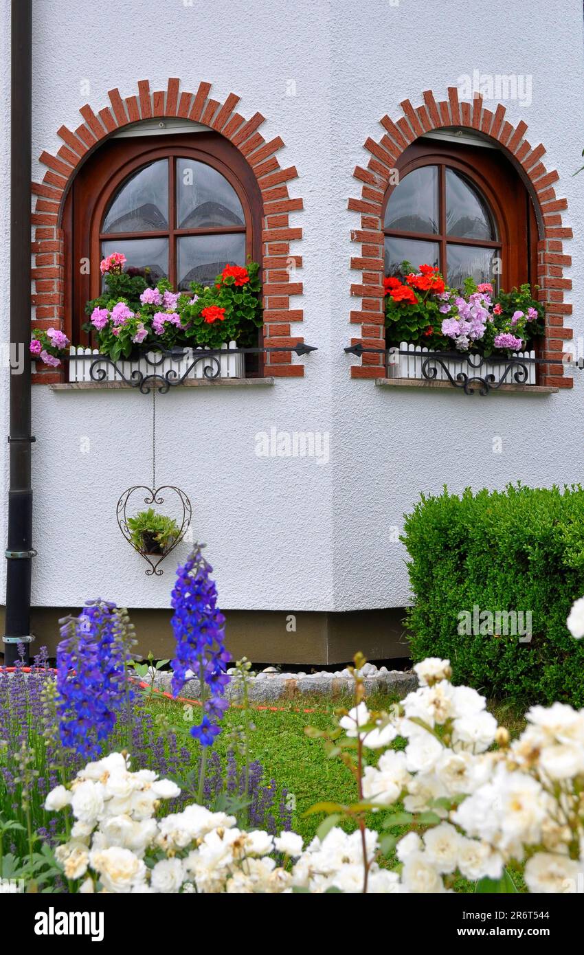 Garden with house, arched window with flowers, geraniums at the window