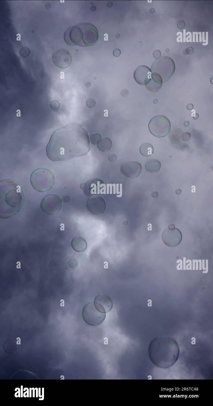 Soap bubbles are flying on gray cloudy sky background Stock Photo