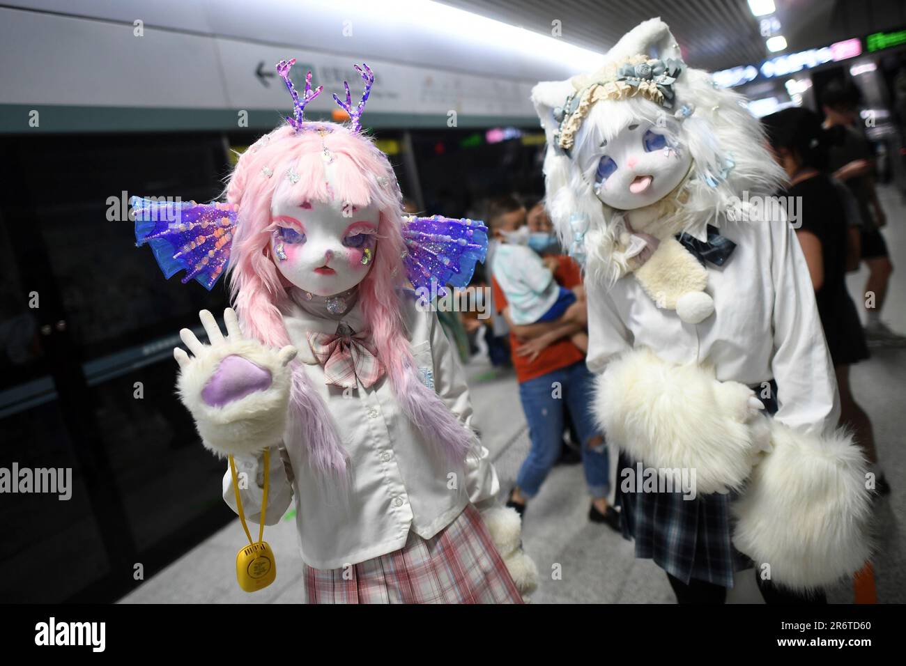 Two cosplayers in furry costumes react to others at a subway station in(07)