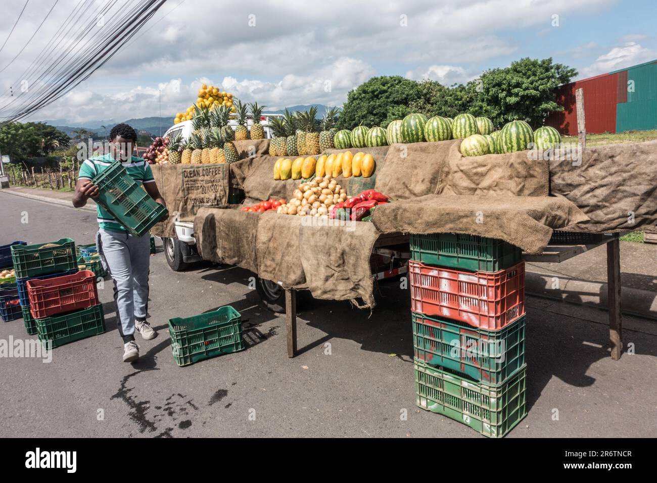 Man unloading fruit and vegetables from plastic crates to display in the bed of a truck in Tres