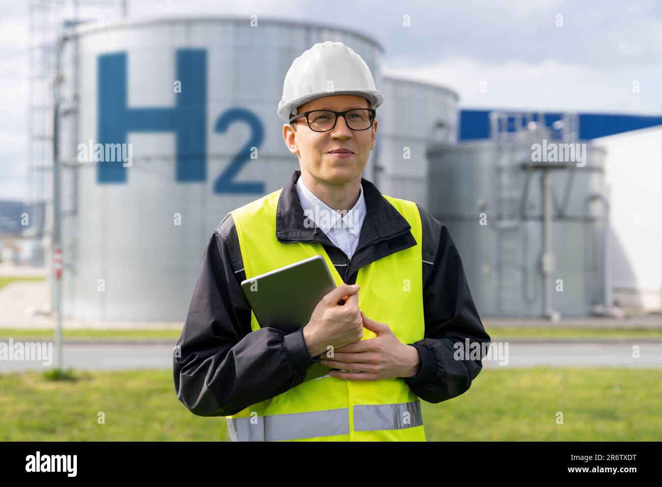 Engineer with tablet computer on a background of Hydrogen factory. Stock Photo