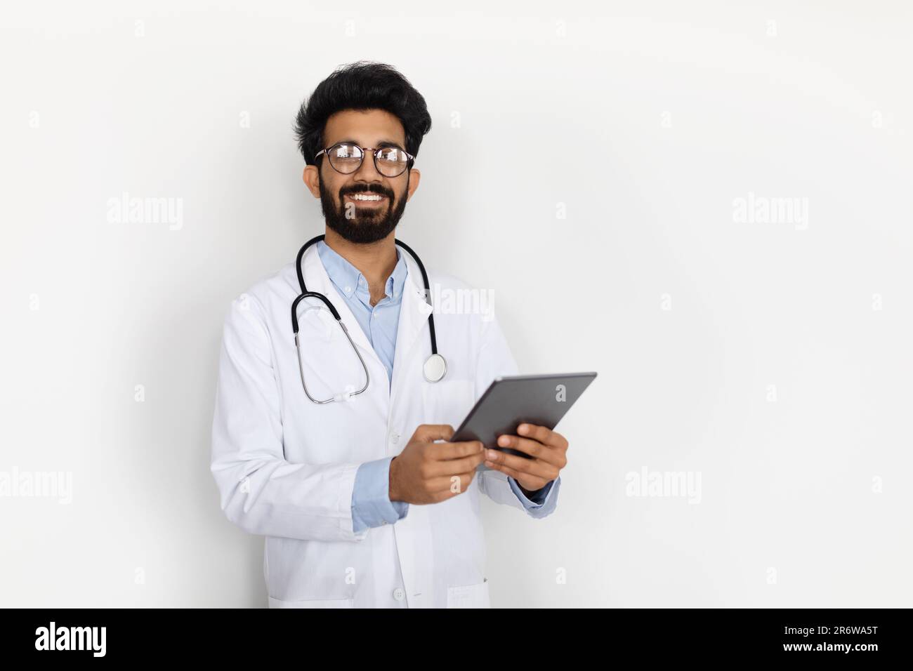 Handsome middle eastern doctor holding digital tablet, white background Stock Photo