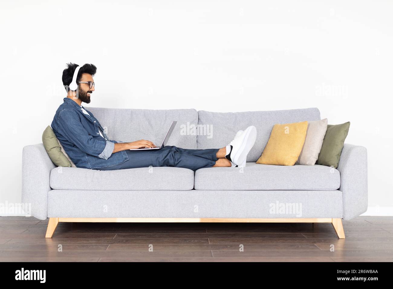 Cheerful arab man developer working from home, using laptop, headphones Stock Photo