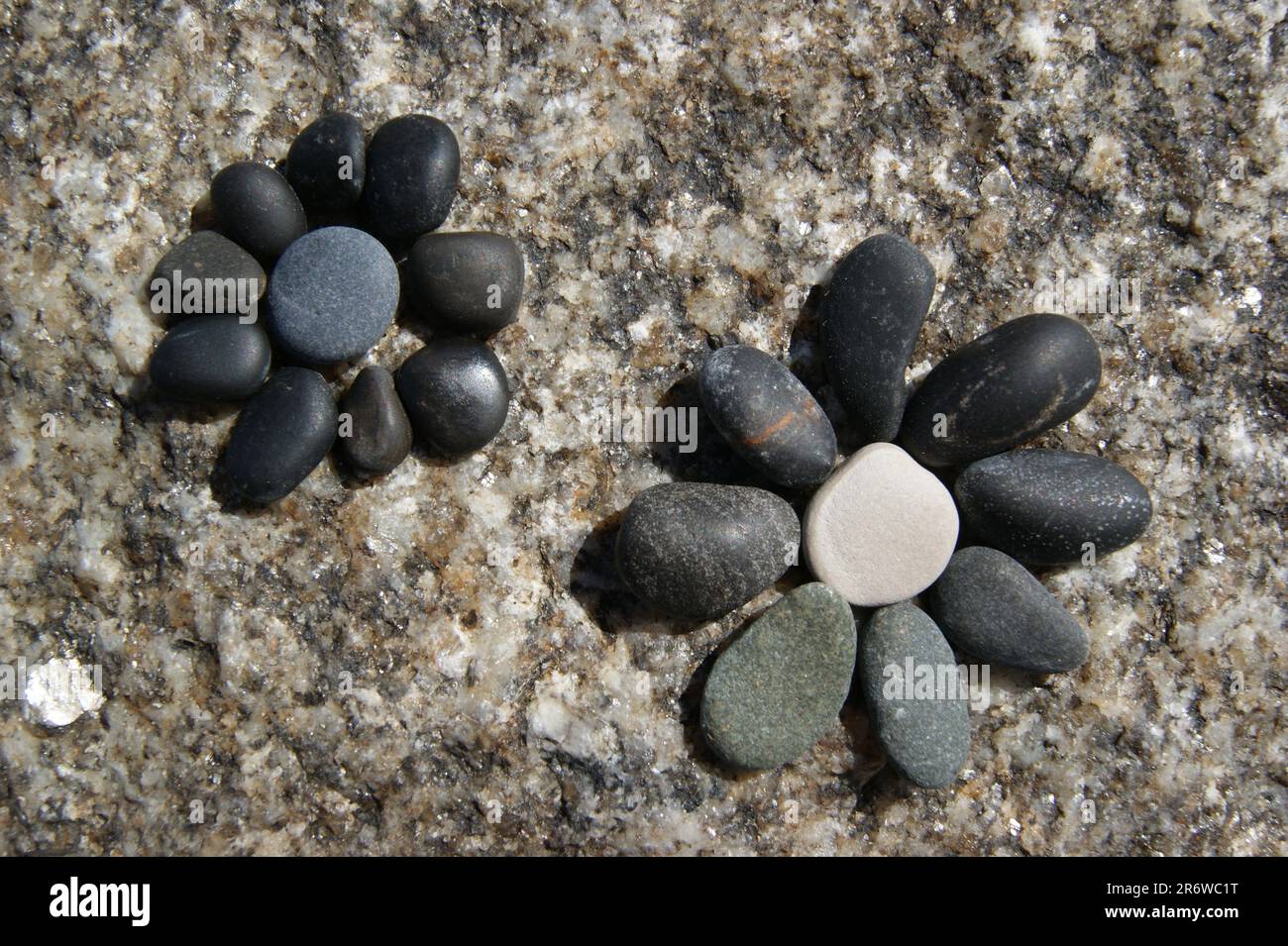 Stone garden decors. A flowers laid out of pebbles on a stone. Stock Photo