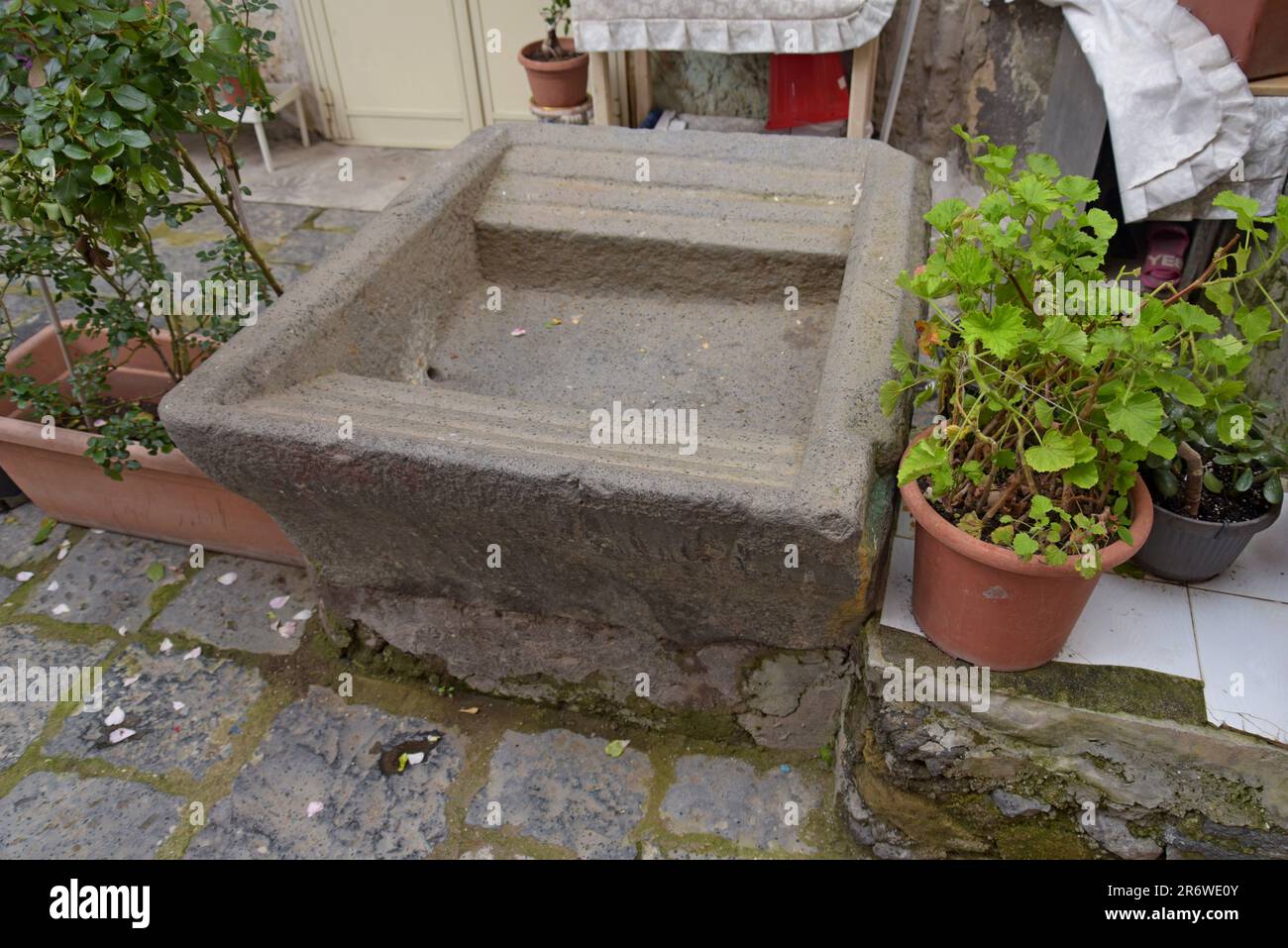 A historic stone trough in a housing courtyard in Naples, Italy, used for clothes washing. Stock Photo