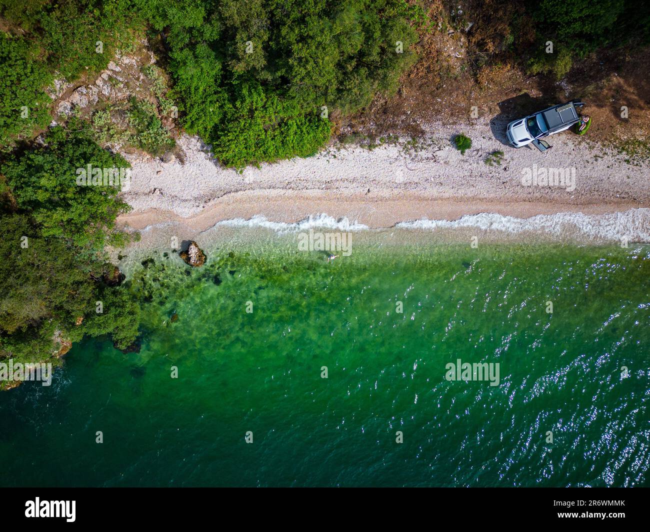 Aerial view of a small beach with clear greenish water with a woman