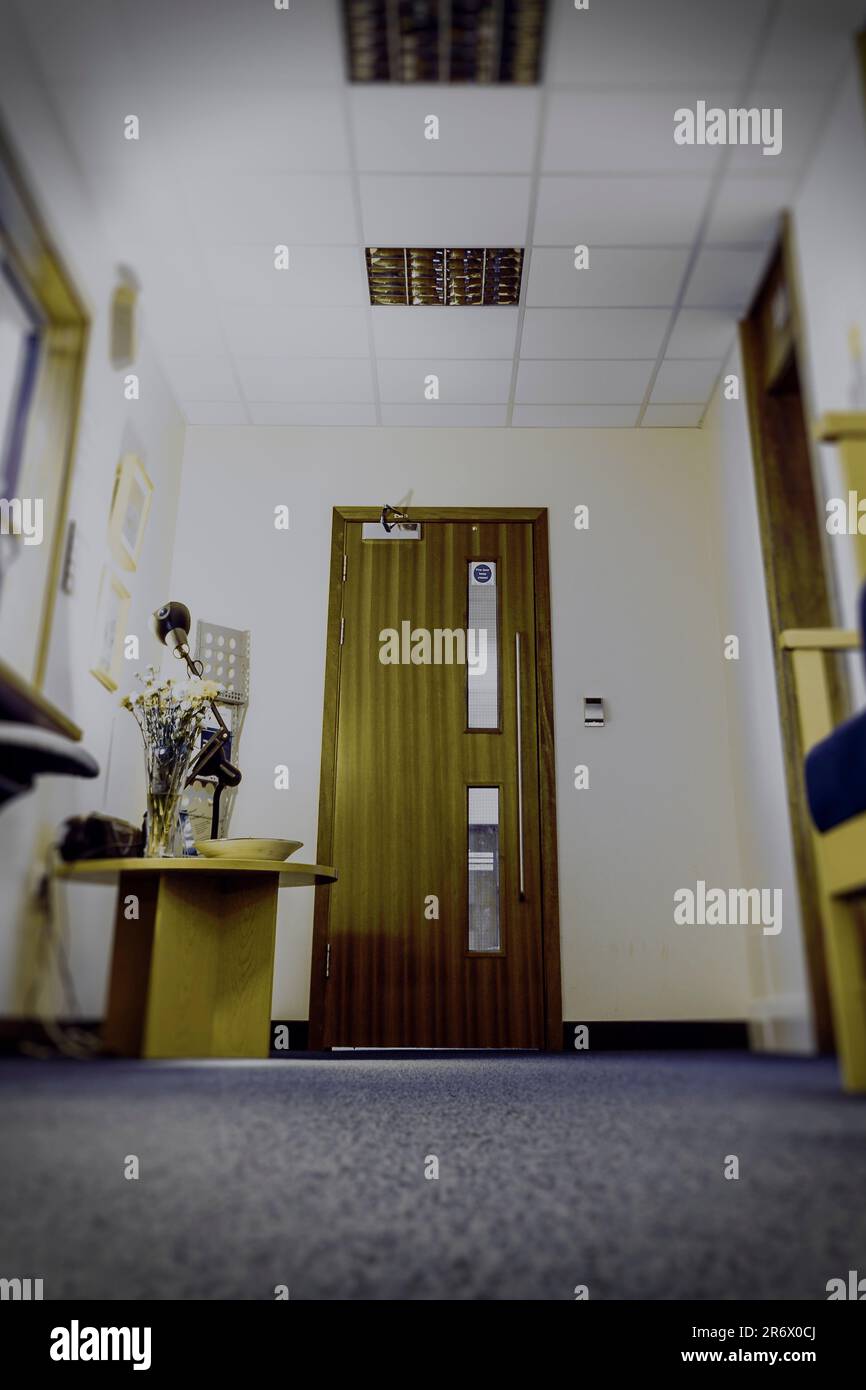 Low angle view of of a door in the dingy reception area of an office or business, selective focus, UK Stock Photo