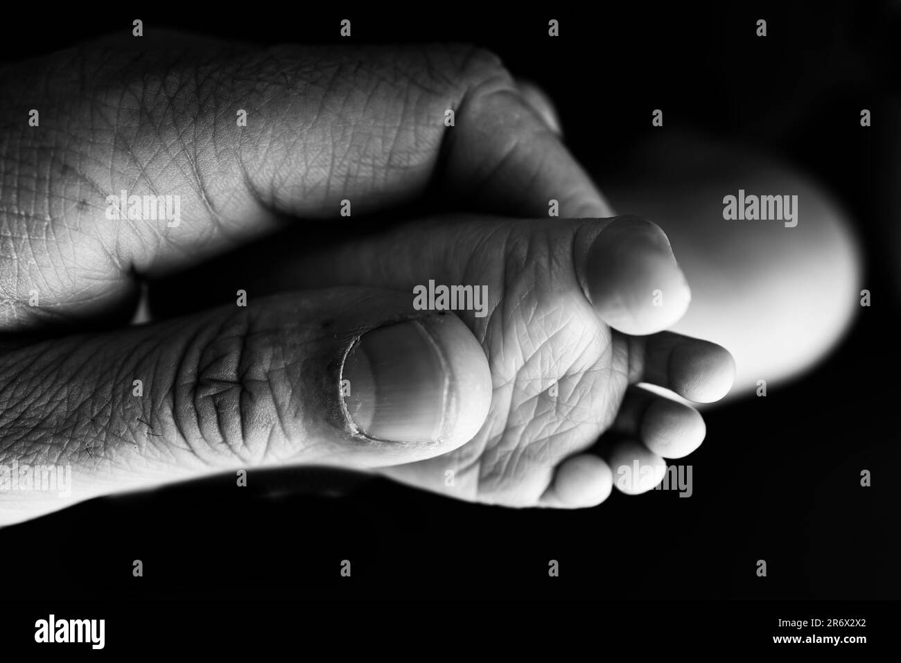 Close up baby feet in mother hands on a black background. Prevention of