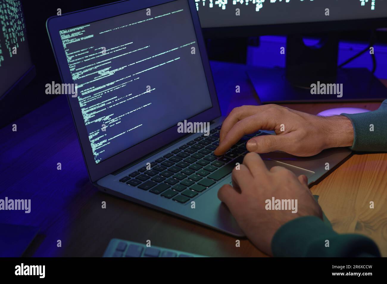Hacker working with computers at wooden table, closeup. Cyber attack Stock Photo