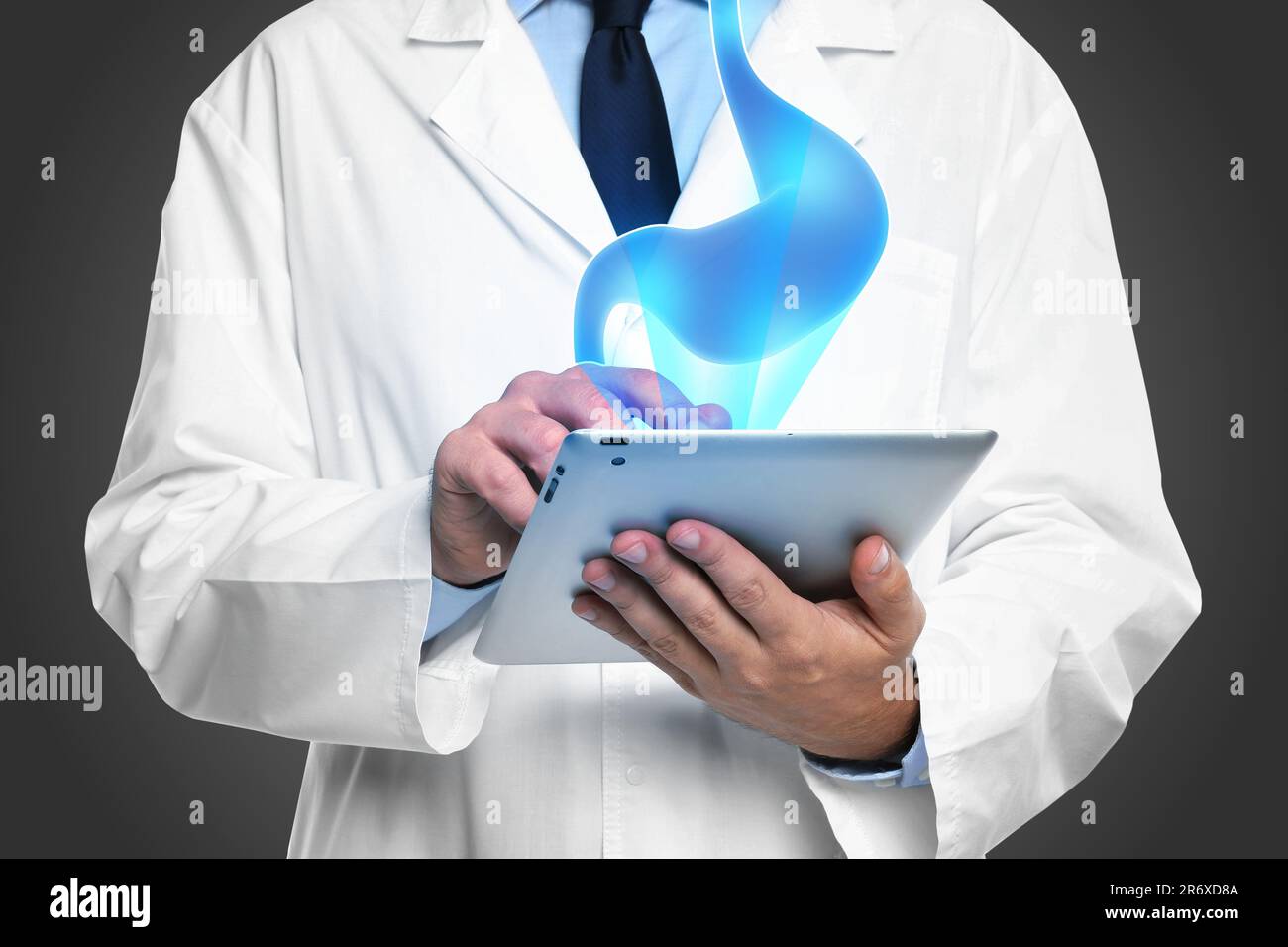 Symptoms and treatment of heartburn and other gastrointestinal diseases. Doctor using tablet on black background, closeup. Stomach illustration over d Stock Photo