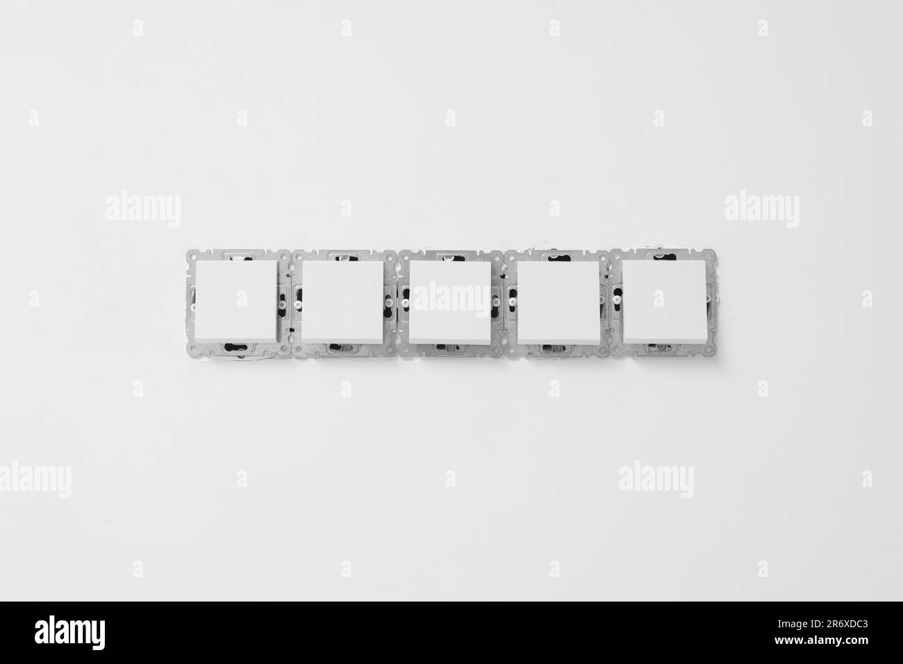 Modern plastic switches on white wall. Installing lighting Stock Photo