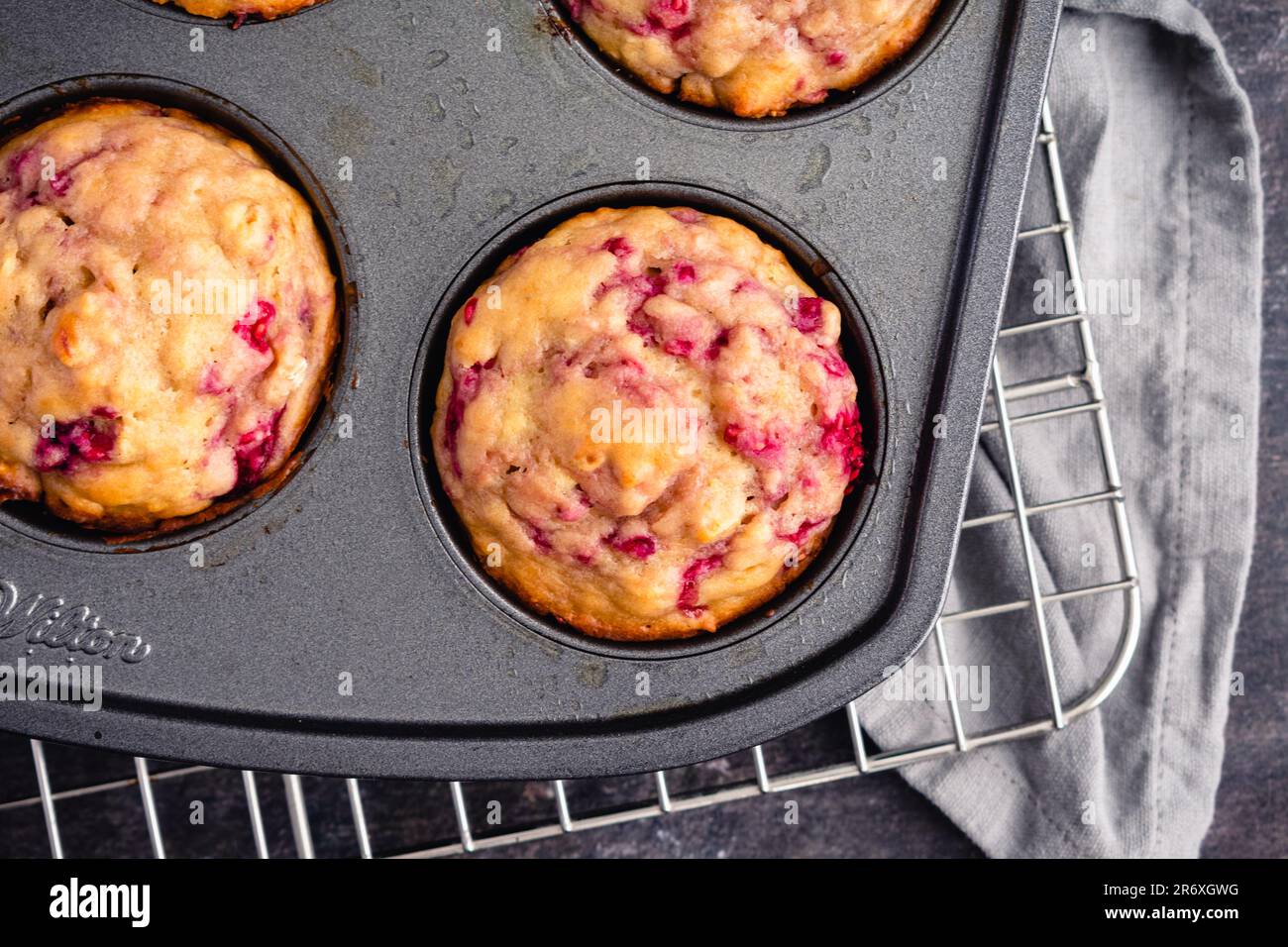 Freshly Baked Raspberry Muffins Closeup in a Nonstick Muffin Pan: Breakfast or dessert muffins made with fruit viewed from above in muffin tin Stock Photo