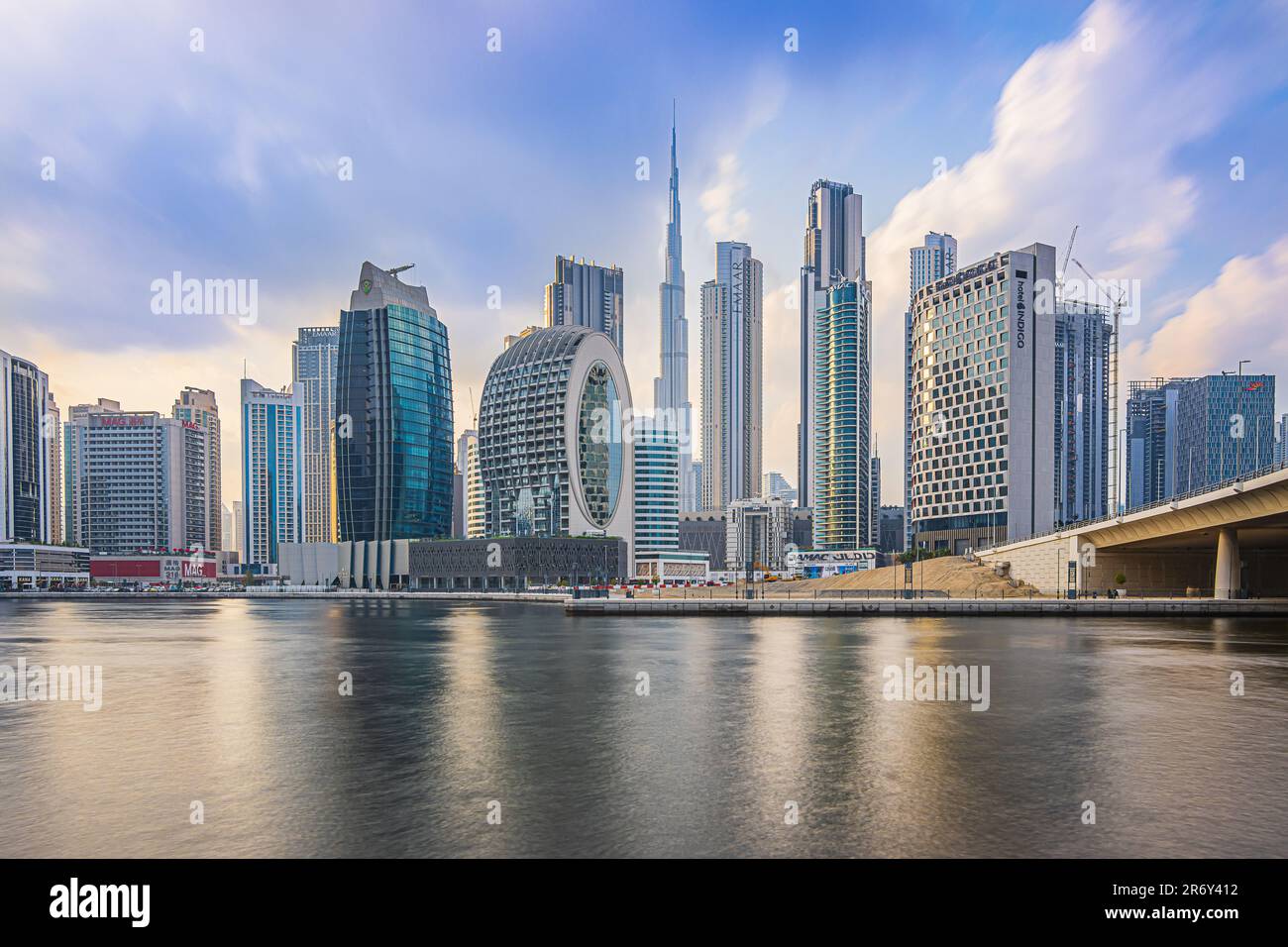 Dubai with skyscrapers and Burj Khalifa in the evening. Skyline with a cloudy sky in the evening mood. Waterfront in Dubai Harbour. Houses with glass Stock Photo